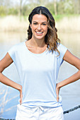Junge Frau in hellblauem T-Shirt und weißen Shorts am Fluss