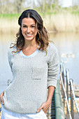 A young woman wearing a grey jumper near river