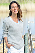 Junge Frau in grauem Pullover und weißen Shorts am Fluss