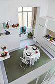 View from gallery down into white interior with kitchen counter and dining table