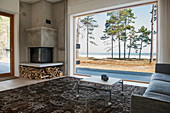 Square corner fireplace in living room with view of sea through panoramic window