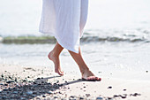 Frau in weißem Bademantel am Strand