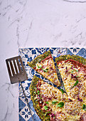 Pizza mit grünem Brokkoli-Spinat-Boden belegt mit Salami und Käse