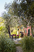 Blick durch mediterranen Garten auf Terrassenplatz vor Haus