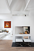 Upholstered stools in front of modern open fireplace in white living room