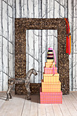 Stacked gift boxes, horse sculpture and picture frame in front of wallpaper with pattern of trees