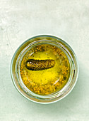 A gherkin in a preserving jar seen from above