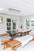 Bänke um einen Tisch mit Glasplatte im sommerlichen Holzhaus