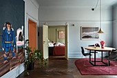 Round dining table in pale blue living room with view into bedroom