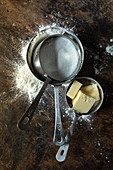 Measuring cups with flour, sugar and butter