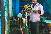 Mann bereitet Kurkuma-Chai-Latte in einer Straßenküche zu (Indien)