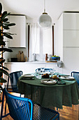 Gedeckter Tisch mit blauen Stühlen in kleiner Wohnküche