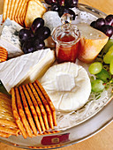 A cheese platter with crackers and grapes