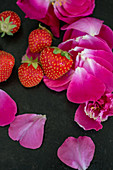 An arrangement of strawberry and pink flower petals