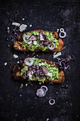 Slices of bread topped with mushy peas and red onions