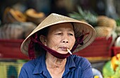 Woman smoking at a market in Hoi An, Vietnam