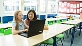 School girl using laptop with teacher