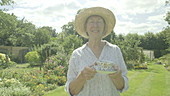 Woman drinking tea in garden, slo-mo