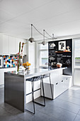 Bar stools and bench with drawers next to counter in modern kitchen