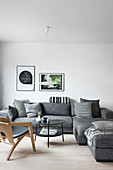 Graues Sofa mit schwarz-weißen Kissen im schlichten Wohnzimmer