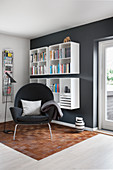 Armchair, magazine rack and wall-mounted shelves in reading area