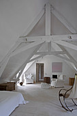 Simple, white attic room with rustic roof beams