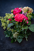 Roses, lady's mantel and hydrangeas on dark surface