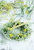 Wreath of cow parsley and buttercups on plate as table decoration for 60th birthday