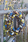 Wreath made of kitten willow with grape hyacinths, gold bells and onions on the fence