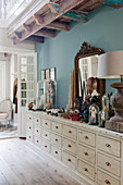Collection of curiosities on sideboard with drawers against blue wall