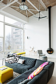 Grey corner sofa in modern living room of loft apartment with suspended fireplace