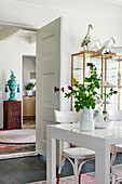 White dining table and chairs in front of display case and open interior door