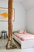 Single bed next to wooden pillar in white room