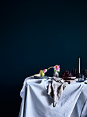Pale tablecloth, pear, flower and grapes on dining table