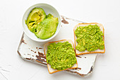 Homemade avocado toasts and smashed fresh ripe avocados in bowl
