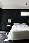 Double bed with white bed linen against black wall