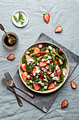 Salad made of grilled asparagus, strawberries, baby spinach, radishes, fresh mint, feta cheese and hazelnuts