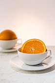Orangenhälfte in weißer Tasse