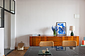 Dining area with wooden sideboard, flower vase and artwork