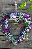 Heart made of lilac blossoms and hemlock on a wooden wall