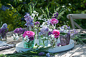 Small bouquets of roses, lilacs, night violes and grasses on a wooden tray