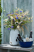 Rural bouquet made from barley, chamomile, cranesbill and Bibernelle bowl with beer bottles and jugs in ice cubes