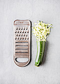 Zucchini, half grated, next to a vegetable grater
