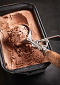 Chocolate ice cream in an ice cream container with an ice cream scoop