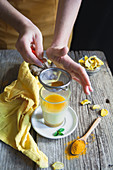 Hands putting turmeric in the milk for the golden milk