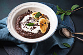 Vegan chocolate semolina porridge with soy yogurt, fried banana and mint