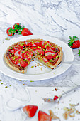 Puff pastry tart with strawberries and pistachios, a piece cut