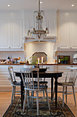 Spoke-back chairs at round table in classic, white kitchen