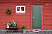 Falu-red Swedish house with green wooden door and simple winter decorations