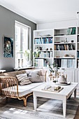 White table, rattan sofa and shelf wall in the living room